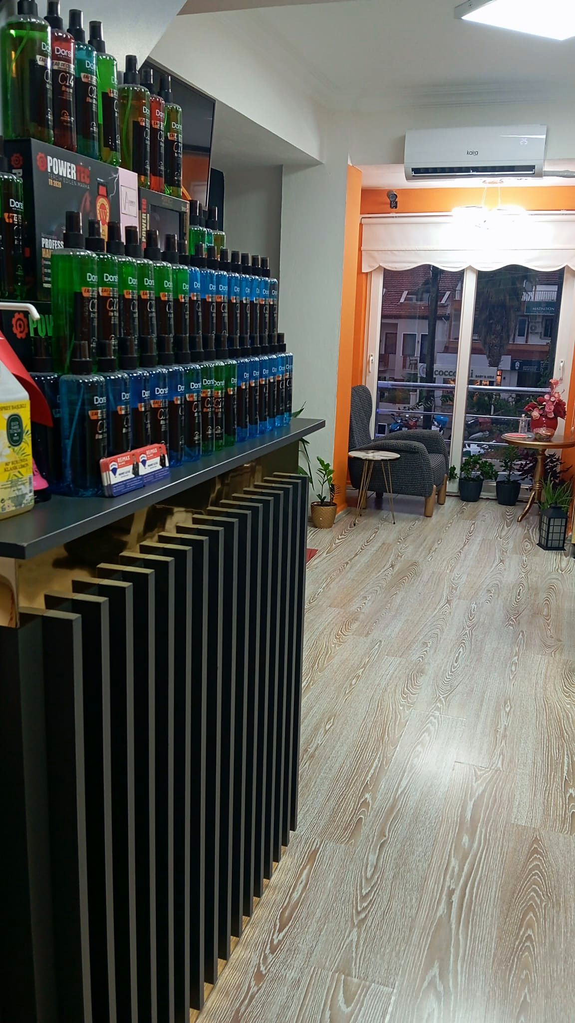 Girişten salonun görünüşü: solda siyah çıtalı tezgâh, sonda pencere önünde koltuklar.